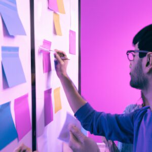 a web designer debating his idea with others in front of a board full of sticky notes